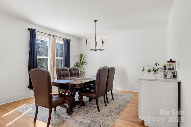 dining space with light wood-type flooring and a notable chandelier