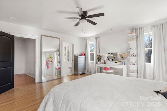 bedroom featuring ceiling fan, multiple windows, and light hardwood / wood-style flooring