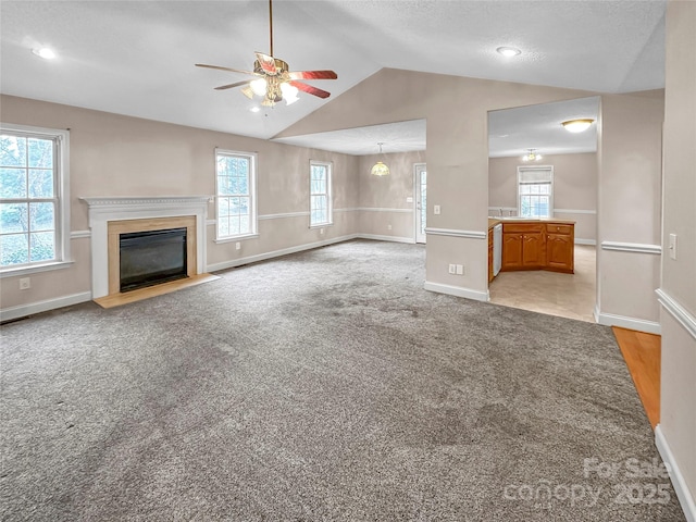 unfurnished living room with vaulted ceiling, light colored carpet, and ceiling fan