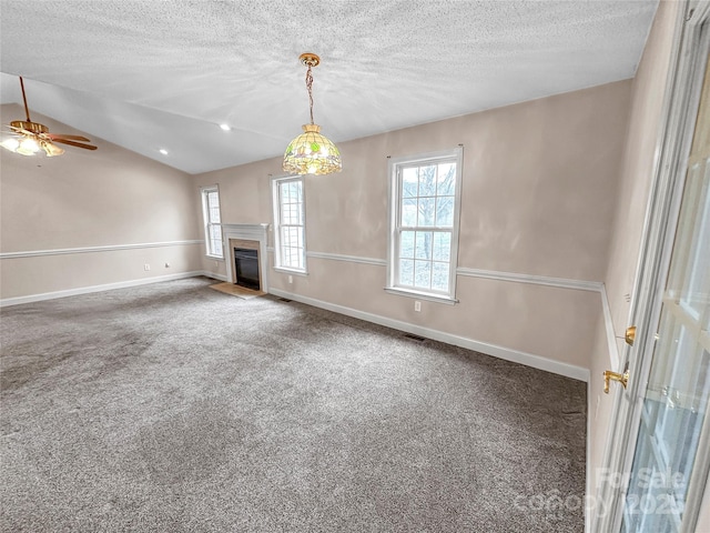 unfurnished living room with lofted ceiling, carpet floors, a wealth of natural light, and a textured ceiling