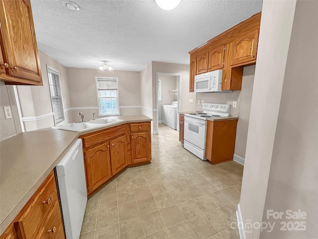 kitchen featuring white appliances, washer / clothes dryer, sink, and a textured ceiling