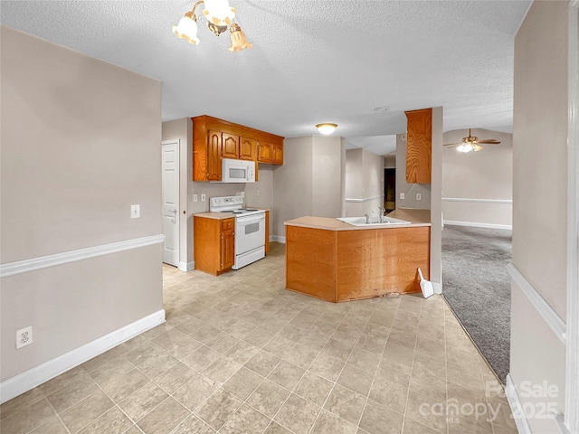 kitchen featuring sink, white appliances, ceiling fan with notable chandelier, light colored carpet, and kitchen peninsula