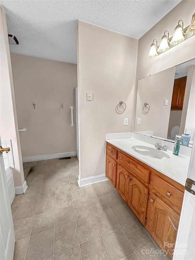 bathroom with tile patterned floors, vanity, and a textured ceiling