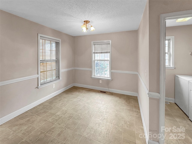 spare room with a chandelier, washing machine and dryer, and a textured ceiling