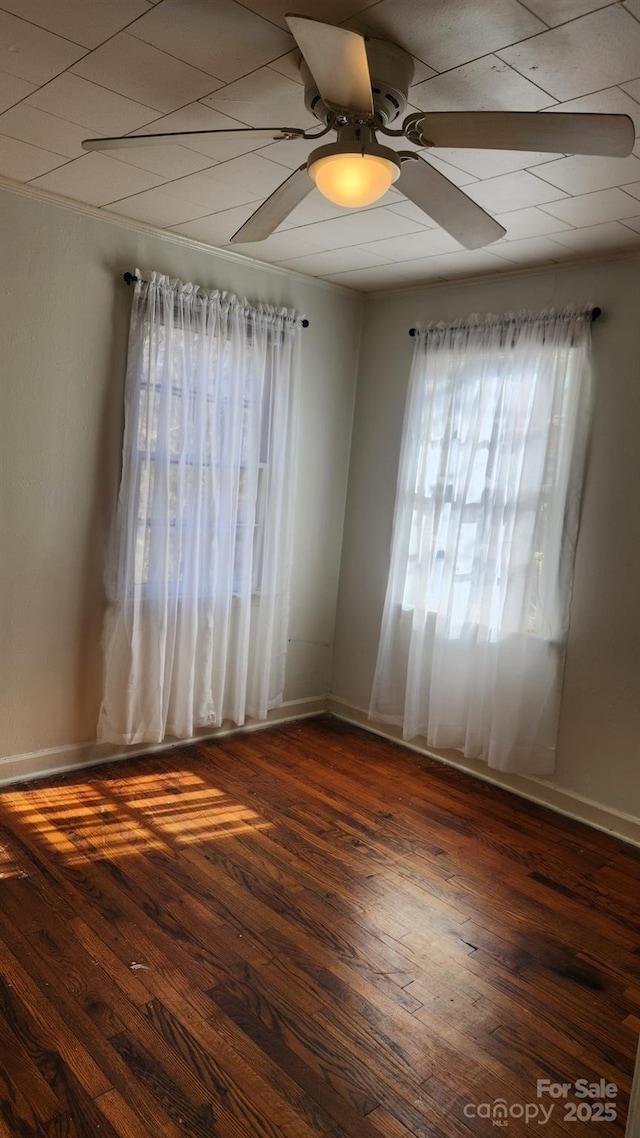 unfurnished room with dark wood-style floors, ceiling fan, and baseboards