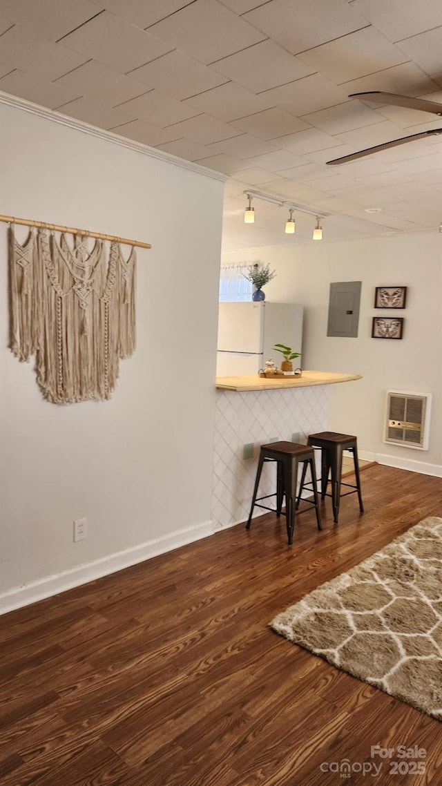 dining room featuring track lighting, electric panel, dark wood finished floors, and baseboards