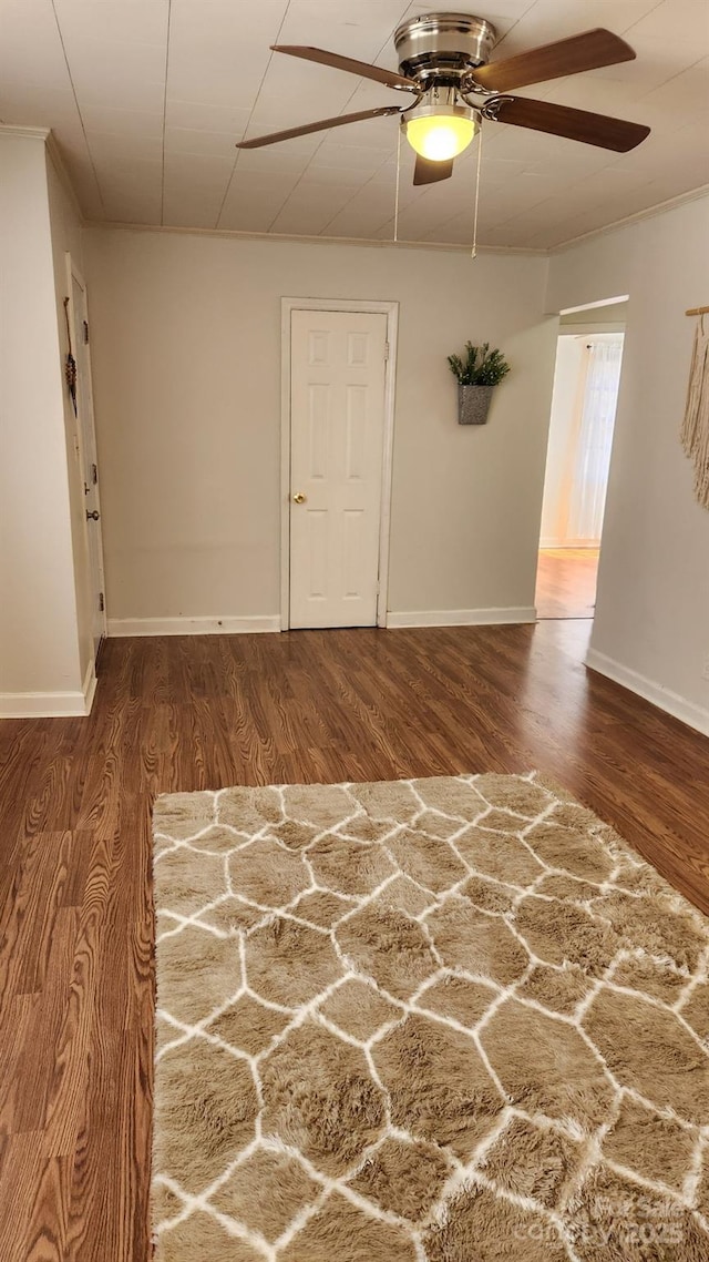 spare room featuring baseboards, dark wood finished floors, and a ceiling fan