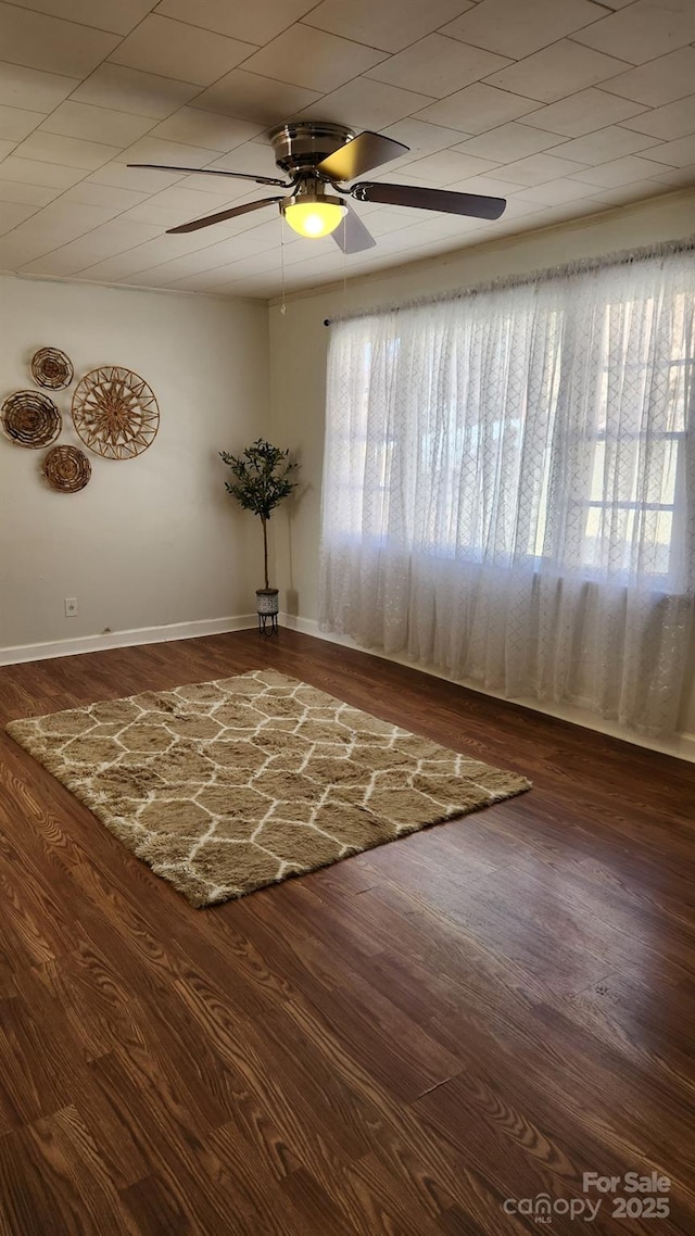 empty room with ceiling fan, baseboards, and wood finished floors