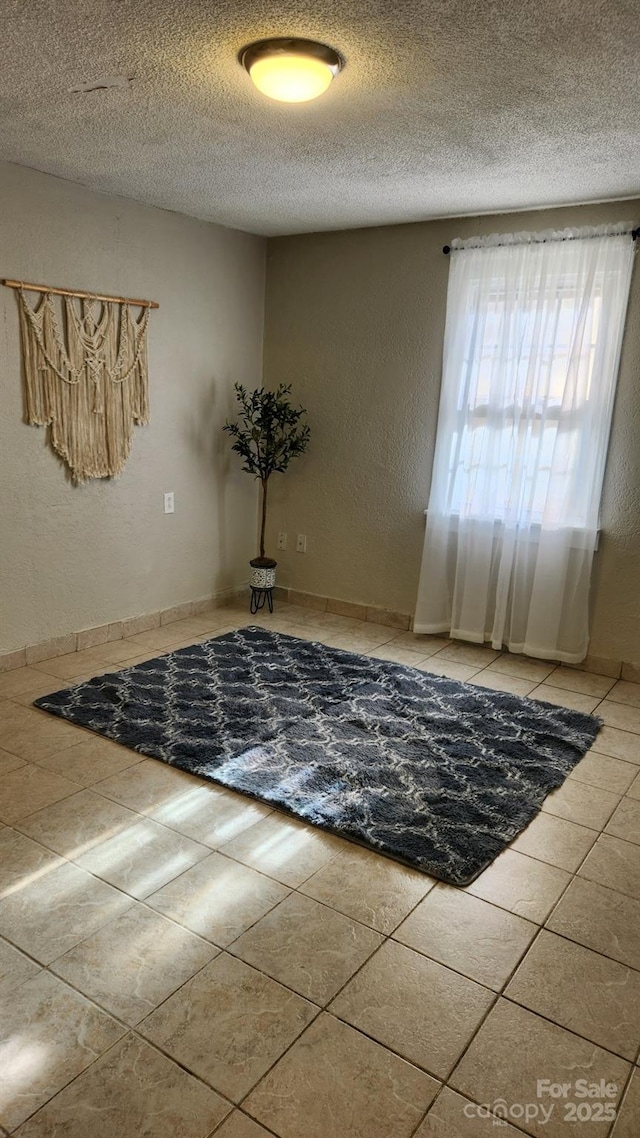 unfurnished room with a textured wall, a textured ceiling, and light tile patterned floors