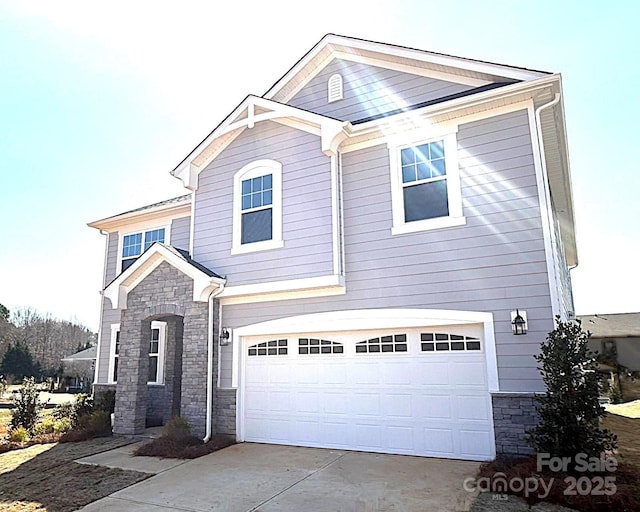 traditional-style home featuring stone siding, an attached garage, and driveway