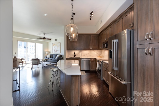 kitchen featuring sink, a breakfast bar area, appliances with stainless steel finishes, a kitchen island, and decorative backsplash