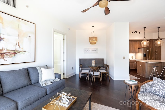 living room featuring ceiling fan and dark hardwood / wood-style flooring