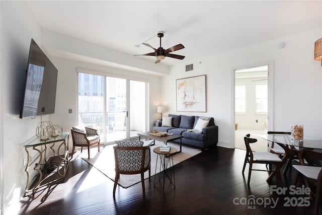 living room featuring a healthy amount of sunlight, dark wood-type flooring, and ceiling fan