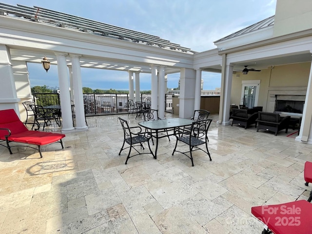 view of patio with an outdoor living space with a fireplace and ceiling fan