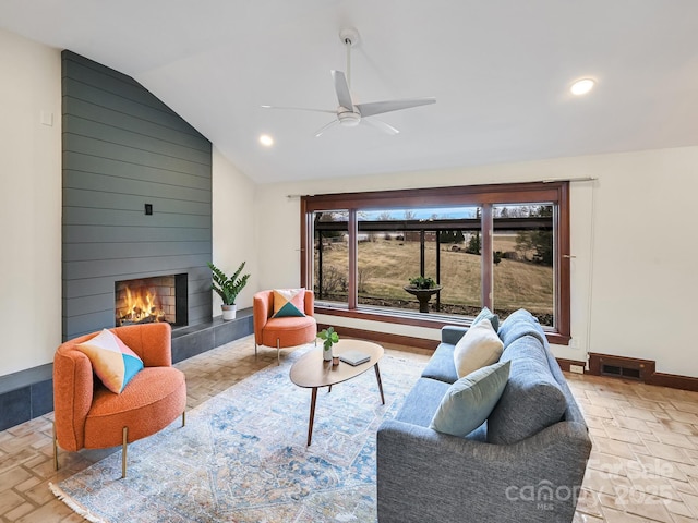 living room featuring ceiling fan, lofted ceiling, and a fireplace