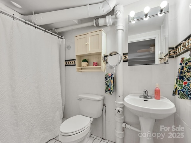 bathroom with tile walls, tile patterned floors, toilet, and a shower with shower curtain