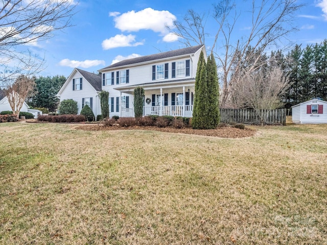 colonial-style house with a front yard, covered porch, and a storage shed