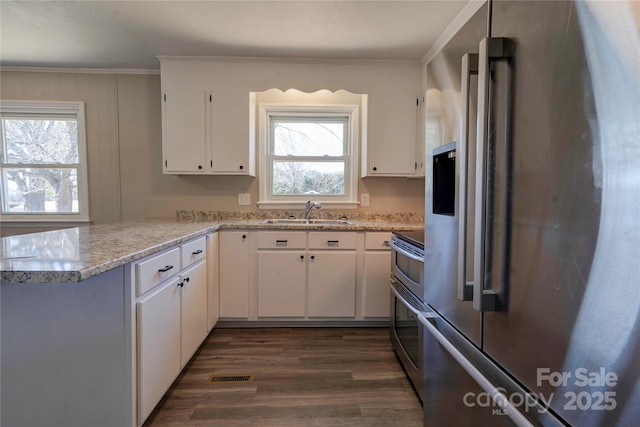 kitchen with sink, white cabinets, ornamental molding, kitchen peninsula, and stainless steel appliances