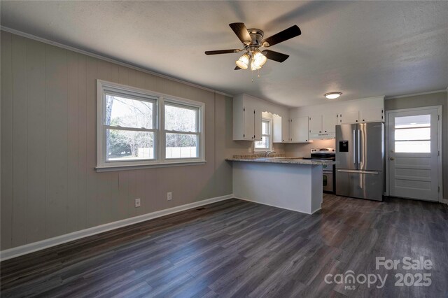 kitchen with white cabinetry, appliances with stainless steel finishes, dark hardwood / wood-style flooring, kitchen peninsula, and plenty of natural light