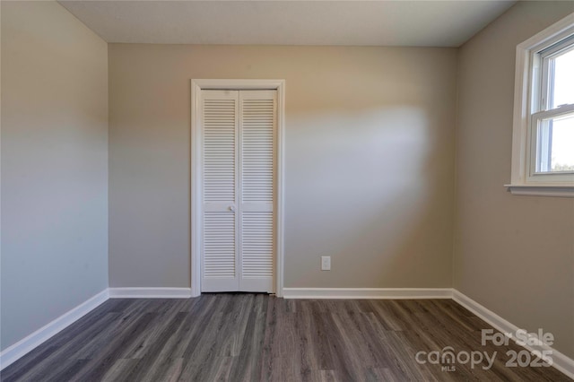 unfurnished bedroom with dark hardwood / wood-style flooring and a closet