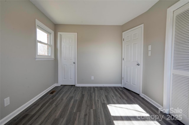 unfurnished bedroom with dark wood-type flooring and a closet