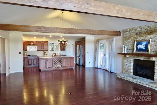 unfurnished living room with dark hardwood / wood-style flooring, vaulted ceiling with beams, a stone fireplace, and a chandelier