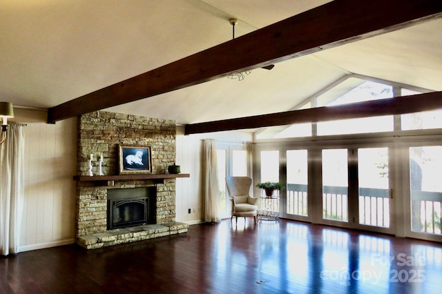 unfurnished living room with hardwood / wood-style flooring, wooden walls, a stone fireplace, and lofted ceiling with beams