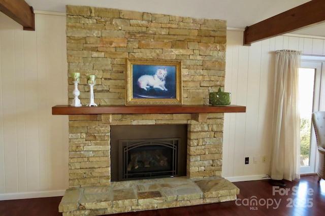 interior details featuring beam ceiling, a stone fireplace, wood walls, and hardwood / wood-style flooring