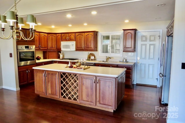 kitchen with pendant lighting, appliances with stainless steel finishes, sink, and a kitchen island