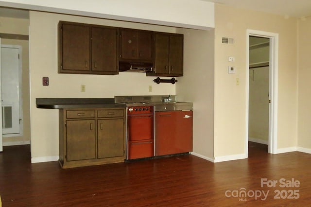 kitchen with stove, dark wood-type flooring, and dark brown cabinetry