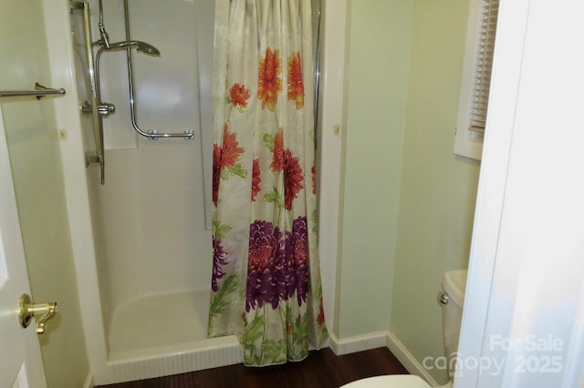 bathroom with hardwood / wood-style flooring, toilet, and walk in shower