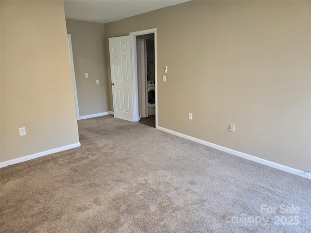 carpeted spare room with washer / dryer