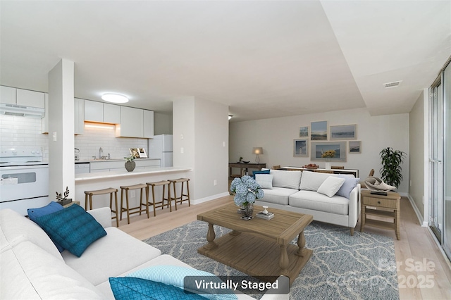 living room featuring sink and light hardwood / wood-style flooring