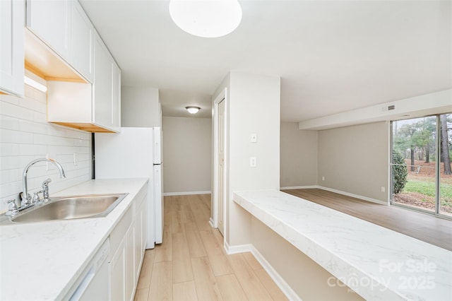 kitchen featuring sink, white appliances, white cabinetry, decorative backsplash, and light wood-type flooring