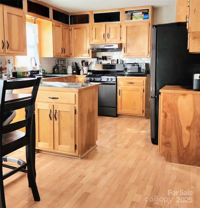 kitchen featuring tasteful backsplash, appliances with stainless steel finishes, light brown cabinets, and light hardwood / wood-style flooring