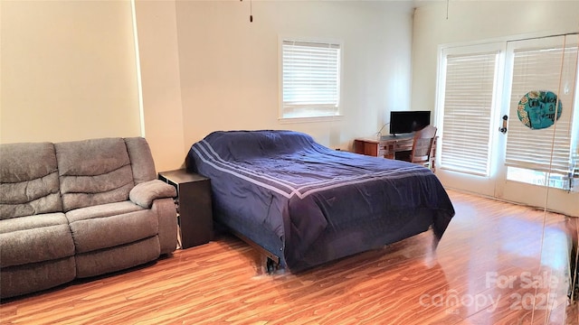 bedroom featuring multiple windows, access to outside, and light hardwood / wood-style floors