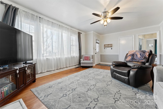 living room featuring light wood-type flooring, ornamental molding, and ceiling fan