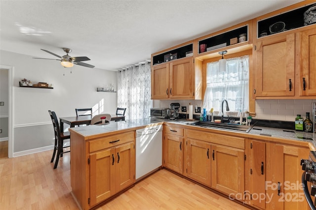 kitchen with sink, tile countertops, light wood-type flooring, and white dishwasher