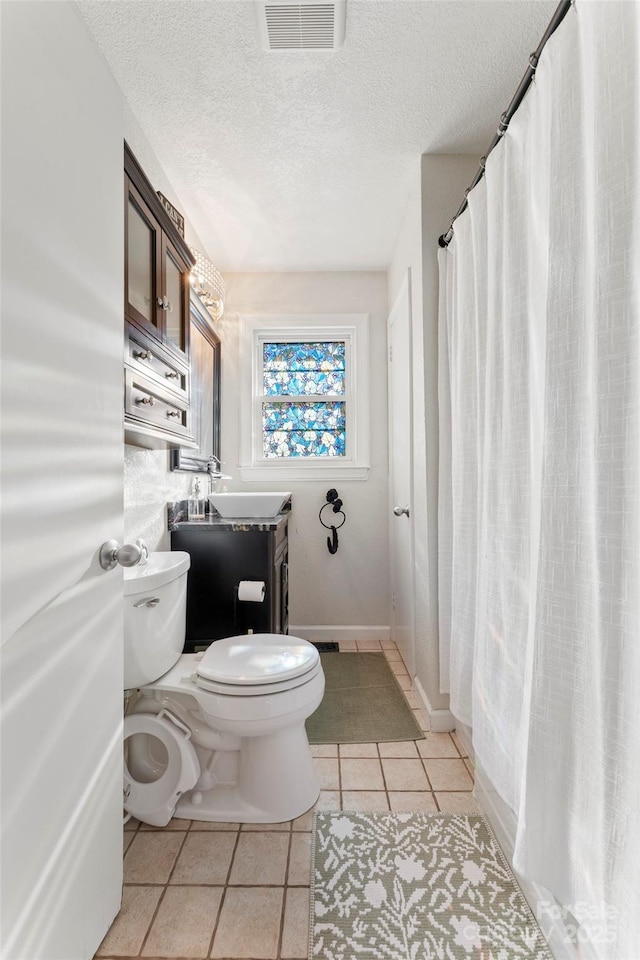 bathroom featuring toilet, sink, tile patterned flooring, and a textured ceiling