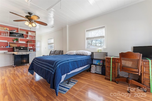 bedroom featuring ceiling fan, multiple windows, wood-type flooring, and crown molding