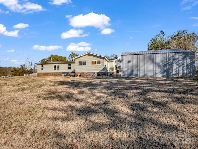 back of house featuring an outbuilding and a yard