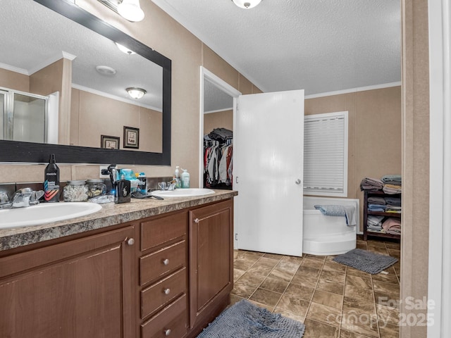 bathroom featuring vanity, crown molding, and a textured ceiling