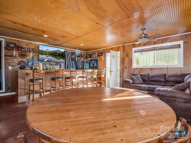 dining space featuring wood ceiling, wood-type flooring, wooden walls, and ceiling fan