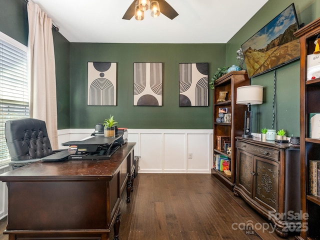 office space with dark wood-style floors, a ceiling fan, a decorative wall, and a wainscoted wall