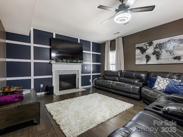 living area with dark wood-style floors, a fireplace, visible vents, and a ceiling fan