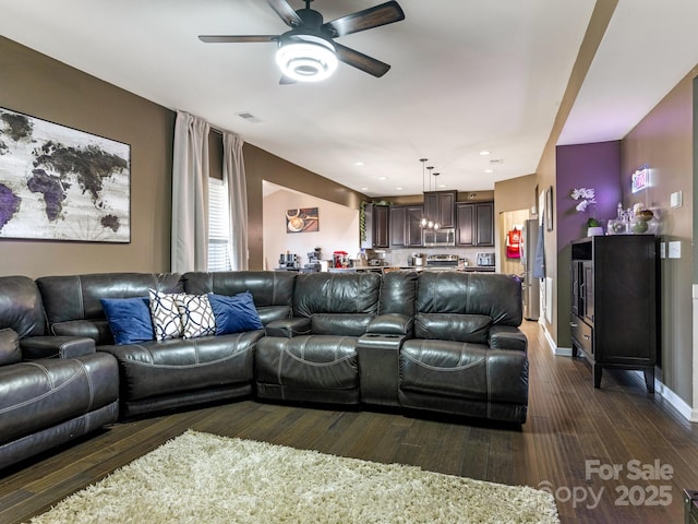 living room featuring dark wood-style flooring, visible vents, ceiling fan, and baseboards