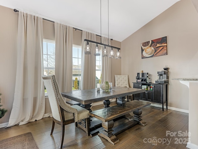 dining room featuring dark wood-style floors, lofted ceiling, and baseboards