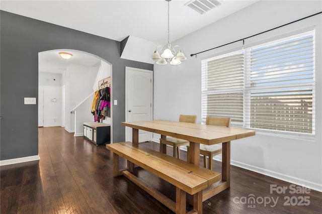 dining room with dark wood-type flooring and a chandelier