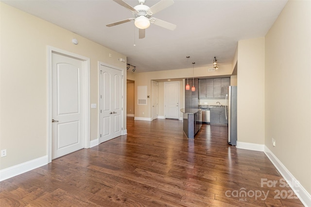 unfurnished living room featuring ceiling fan, sink, and dark hardwood / wood-style flooring