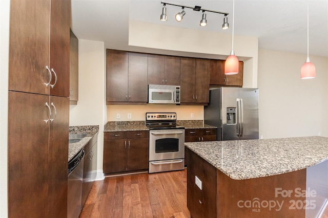 kitchen with dark brown cabinetry, stainless steel appliances, and decorative light fixtures